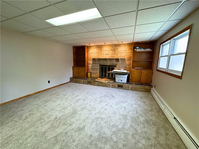 unfurnished living room featuring built in features, carpet floors, a fireplace, baseboard heating, and baseboards