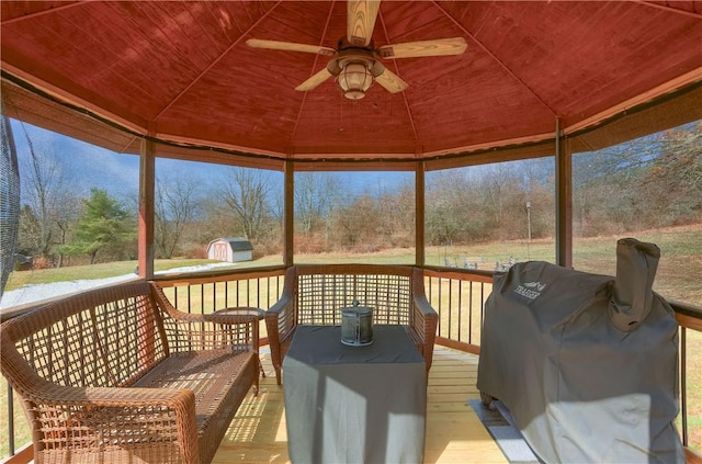 wooden terrace with ceiling fan, a grill, an outdoor hangout area, and a gazebo