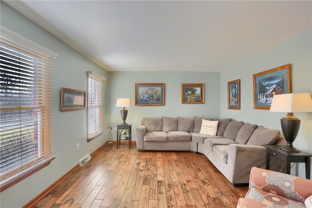 living area featuring baseboards, visible vents, and light wood finished floors