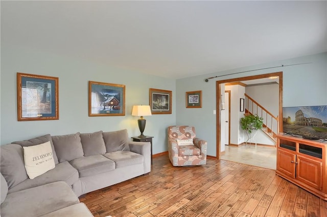 living room featuring light wood-style flooring, stairs, and baseboards