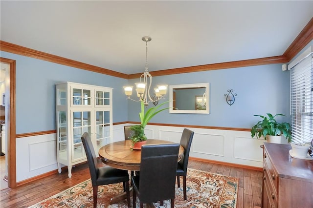 dining room featuring a notable chandelier, crown molding, hardwood / wood-style floors, and wainscoting