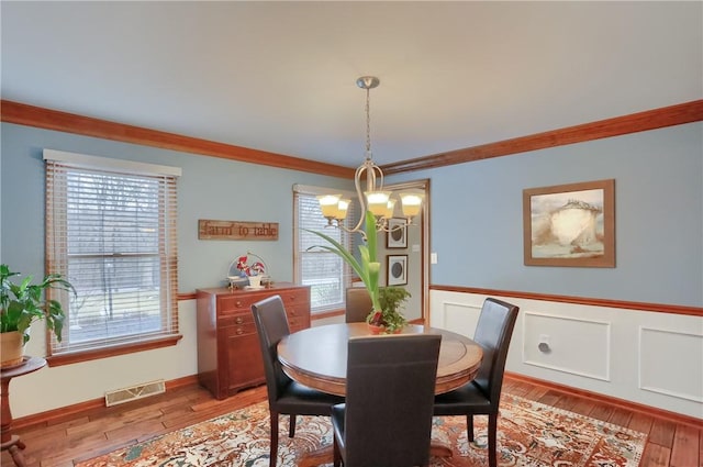 dining space featuring a chandelier, light wood-type flooring, visible vents, and a healthy amount of sunlight