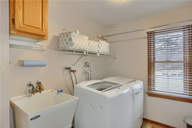 laundry area featuring cabinet space, washing machine and dryer, baseboards, and a sink