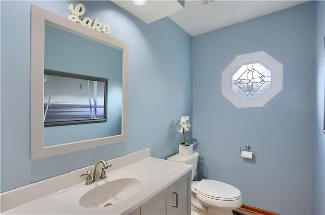 half bath with toilet, visible vents, and vanity