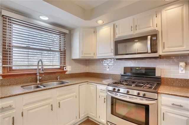 kitchen featuring appliances with stainless steel finishes, a sink, white cabinets, and tasteful backsplash