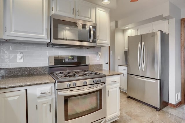 kitchen featuring dark countertops, white cabinetry, stainless steel appliances, and backsplash