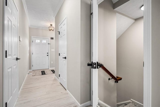 hallway featuring baseboards, crown molding, and wood finished floors