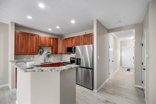 kitchen with baseboards, stainless steel appliances, light wood-type flooring, a sink, and recessed lighting