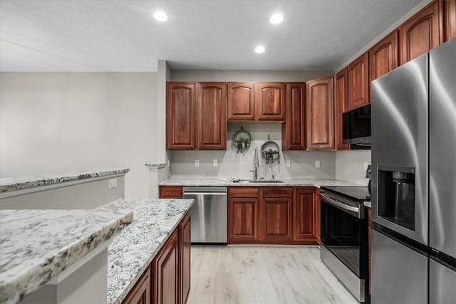 kitchen with light stone counters, stainless steel appliances, recessed lighting, light wood-style floors, and a sink