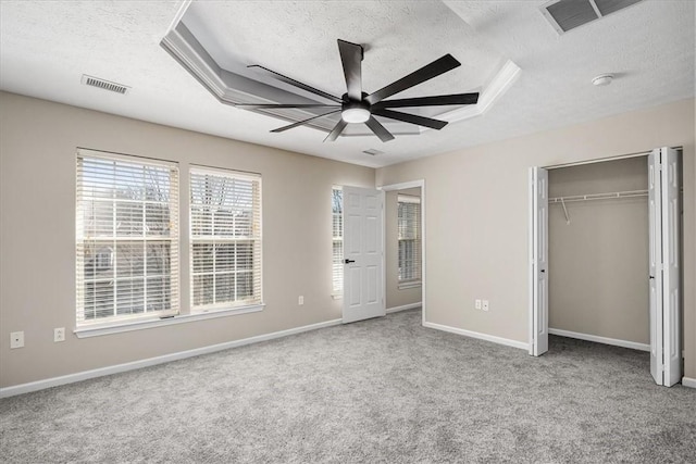 unfurnished bedroom with carpet floors, visible vents, a textured ceiling, and baseboards