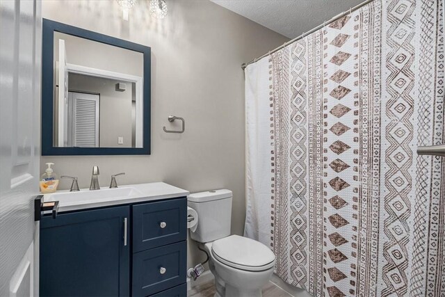 full bath with curtained shower, vanity, toilet, and a textured ceiling