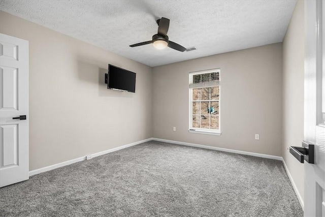 carpeted spare room featuring a ceiling fan, visible vents, a textured ceiling, and baseboards