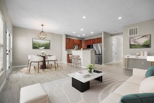 living room featuring recessed lighting, baseboards, visible vents, and light wood finished floors