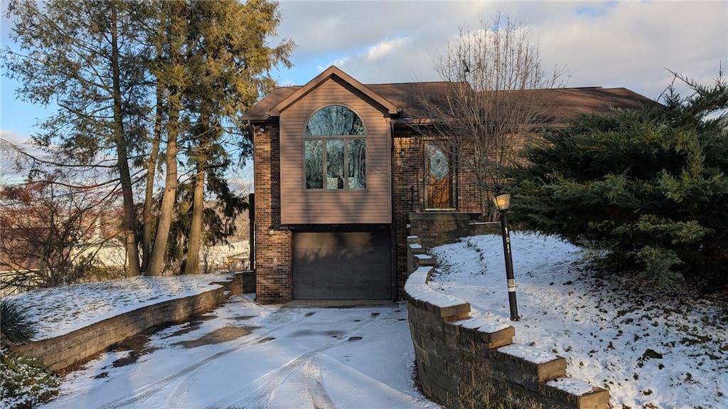 snow covered structure featuring an attached garage