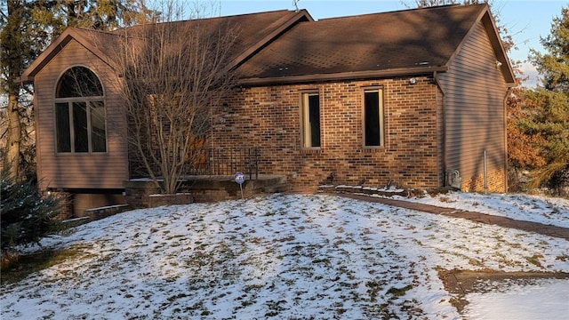 snow covered property featuring brick siding