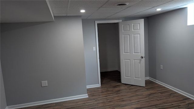 interior space with a drop ceiling, dark wood finished floors, visible vents, and baseboards