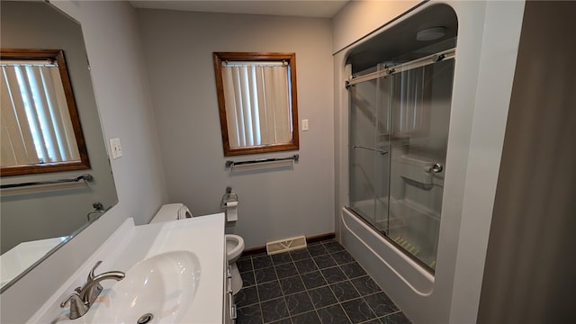 bathroom with visible vents, toilet, combined bath / shower with glass door, a sink, and tile patterned flooring