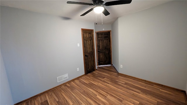 unfurnished room with ceiling fan, wood finished floors, visible vents, and baseboards