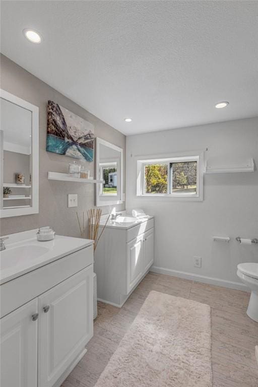 bathroom with recessed lighting, baseboards, vanity, and toilet