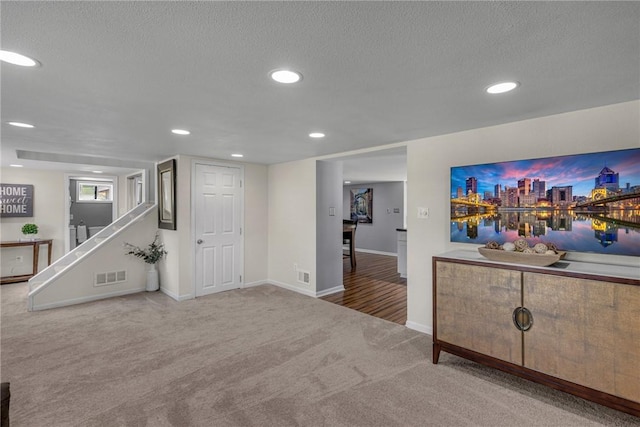 interior space with carpet floors, recessed lighting, visible vents, stairway, and a textured ceiling