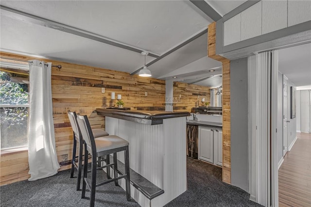 bar with pendant lighting, dark carpet, bar area, and wooden walls