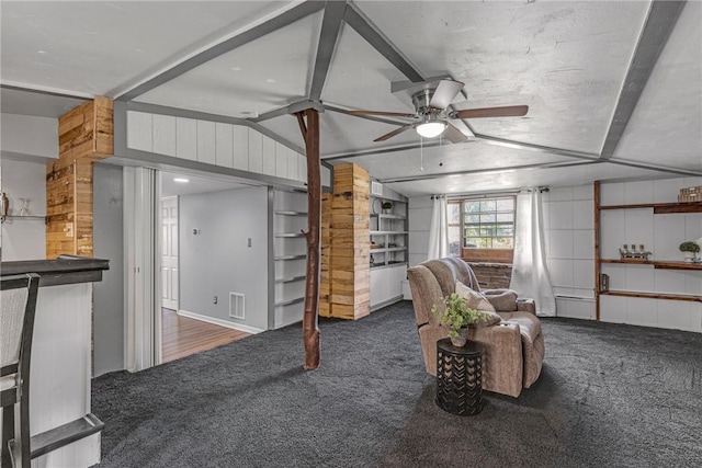 living room featuring carpet floors, lofted ceiling, visible vents, ceiling fan, and wooden walls