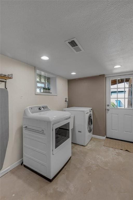 laundry room with baseboards, washing machine and dryer, visible vents, and a textured ceiling