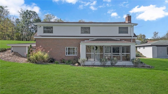 rear view of house featuring a yard, a chimney, a sunroom, and brick siding