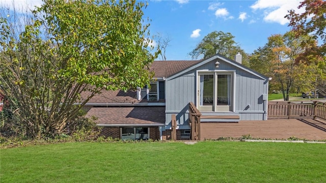 back of house featuring brick siding, fence, a yard, roof with shingles, and a chimney