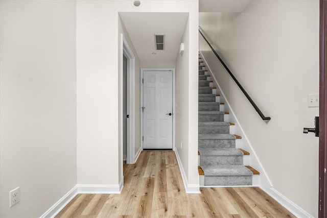 stairway featuring baseboards, visible vents, and wood finished floors