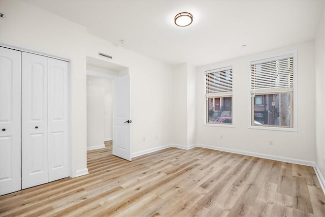 unfurnished bedroom with light wood-style flooring, a closet, visible vents, and baseboards