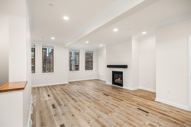 unfurnished living room with baseboards, light wood-type flooring, a glass covered fireplace, and crown molding