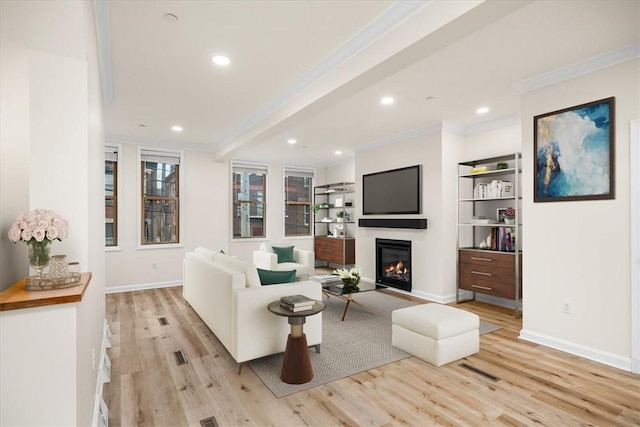 living area featuring recessed lighting, baseboards, ornamental molding, light wood finished floors, and a glass covered fireplace