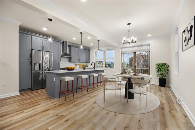 dining space featuring light wood-style floors, a notable chandelier, baseboards, and crown molding