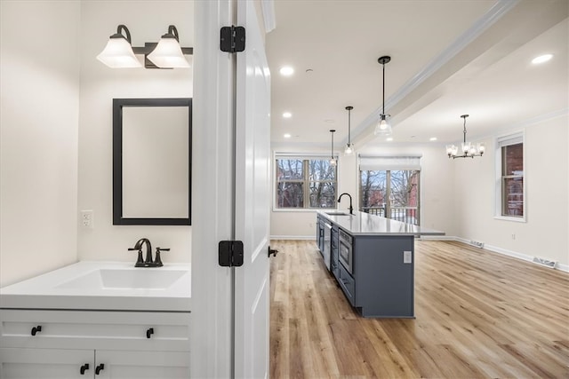 kitchen with crown molding, light wood-style flooring, and a sink