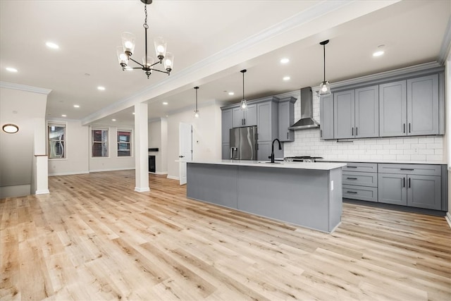 kitchen with stainless steel fridge with ice dispenser, wall chimney exhaust hood, gray cabinets, crown molding, and light countertops