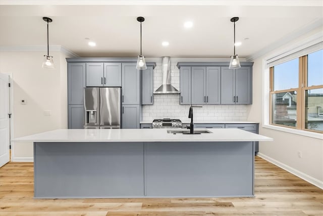 kitchen with gray cabinetry, a sink, ornamental molding, wall chimney exhaust hood, and stainless steel fridge