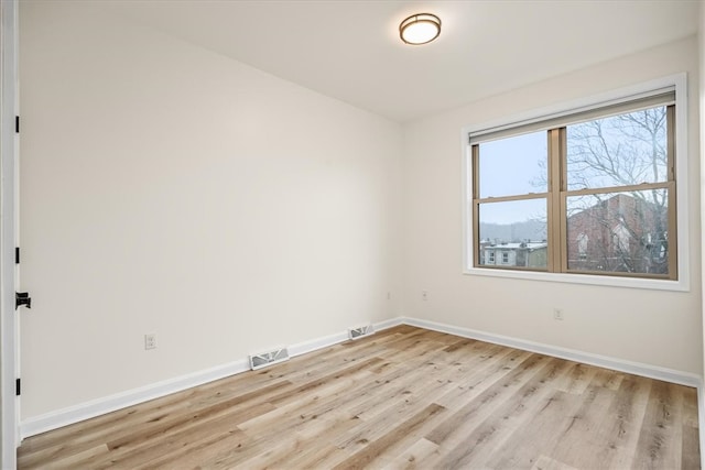 empty room featuring baseboards, visible vents, and light wood-style floors