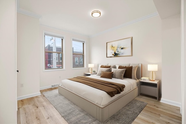 bedroom featuring ornamental molding, light wood-type flooring, and baseboards