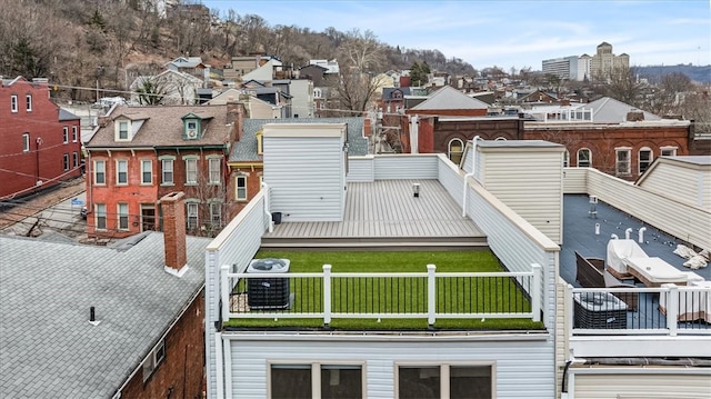 back of house featuring a lawn, cooling unit, and a residential view