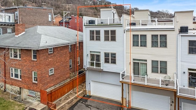 back of property with a garage, aphalt driveway, and central air condition unit