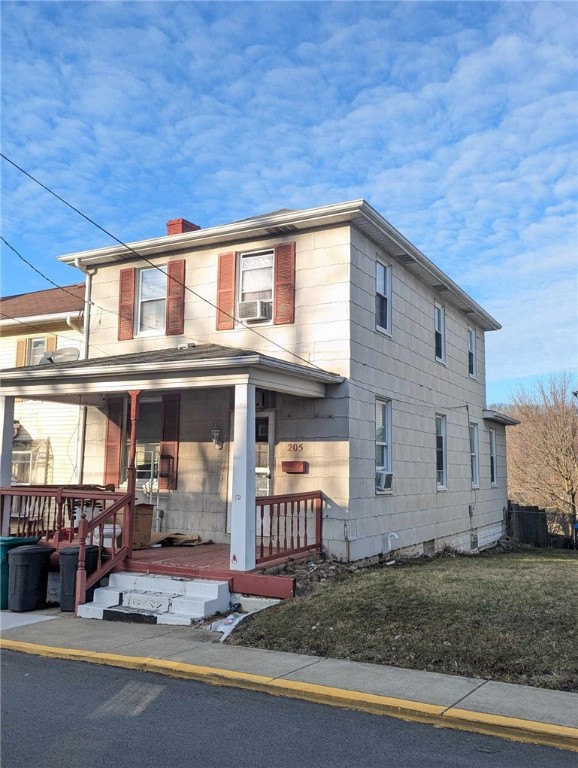 view of front facade with a porch, a chimney, cooling unit, and a front lawn