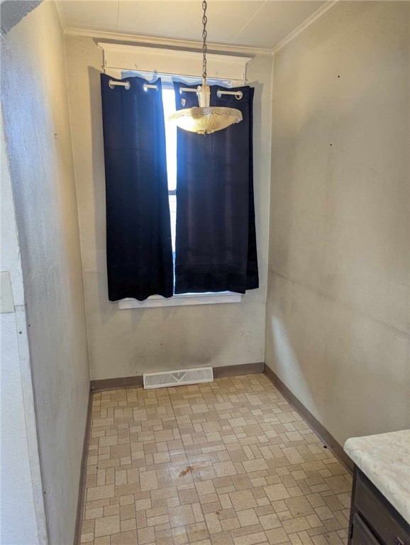 spare room featuring ornamental molding, brick patterned floor, visible vents, and baseboards