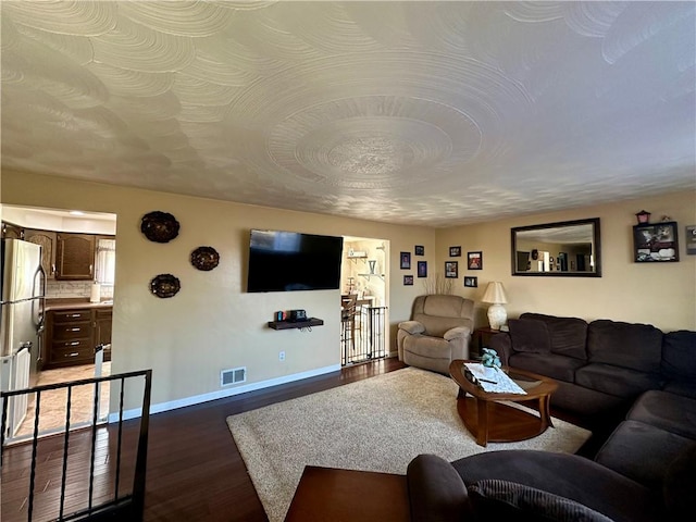 living area with baseboards, visible vents, and dark wood-type flooring