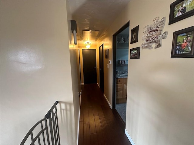 corridor featuring dark wood-style floors, baseboards, and an upstairs landing