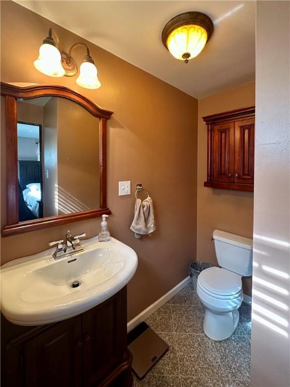 half bath featuring vanity, toilet, and baseboards