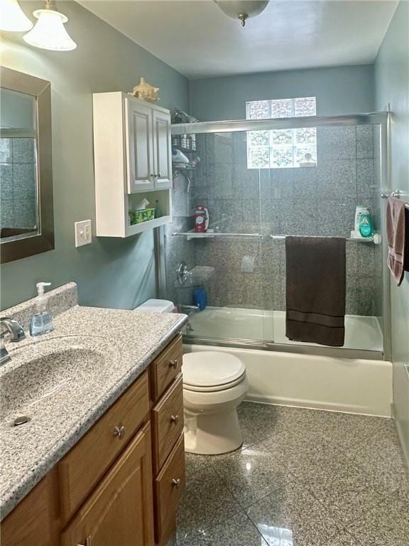 full bathroom featuring toilet, shower / bath combination with glass door, granite finish floor, and vanity