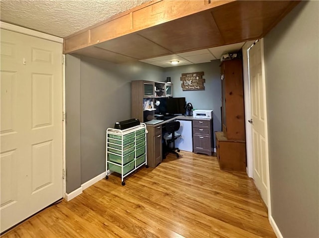 home office featuring light wood finished floors, a paneled ceiling, and baseboards