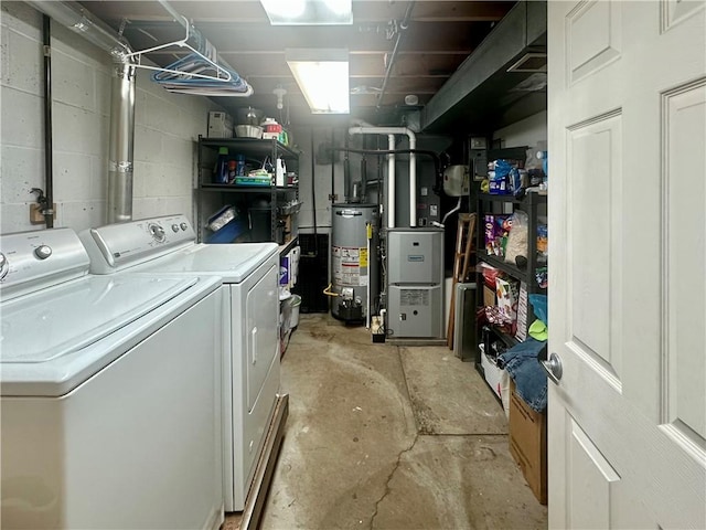 washroom featuring concrete block wall, laundry area, washer and dryer, and gas water heater