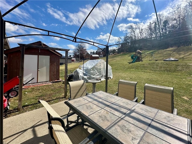 view of patio with outdoor dining area, a playground, an outdoor structure, and a shed